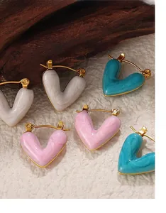 Makroaufnahme süßer Herzohrringe in Gold mit weißem rosa und blauem Marmor-Emaille-Dekor