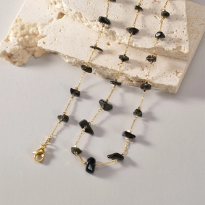 Detail of bohemian gold chain necklace with natural black stone fragments on stone decor