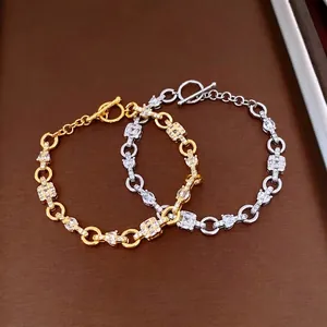 Gold and silver square zircon bracelets with toggle clasp on a textured surface