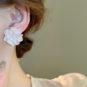 Macro shot of large camellia flower stud earrings with pearlescent pink and white petals