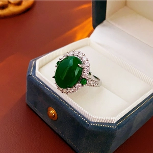 Detailed view of an oval green gemstone ring with pavé diamonds in a blue velvet box