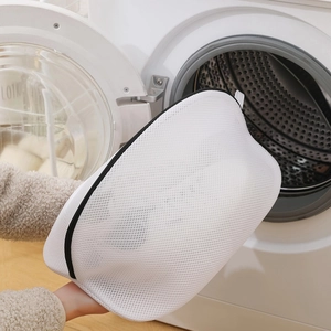 Mesh laundry bag for shoes held near a washing machine for laundry protection