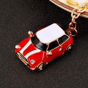 Close-up of red rhinestone beetle car keychain with white racing stripes on golden chain