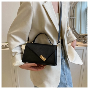 Detail of black animal-embossed leather handbag with golden metal twist lock and shoulder strap