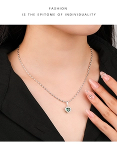 Detail shot of a heart-shaped pendant with a green gemstone on a 925 sterling silver chain
