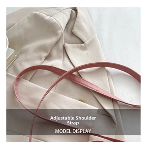 Detail of adjustable pink leather strap with fine stitching on a beige blazer background