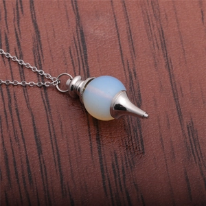 Close-up of a silver necklace featuring an opal-style white bead with a pointed metal cone