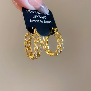 Macro shot of 925 silver gold-plated hollow chain earrings with sparkling rhinestones