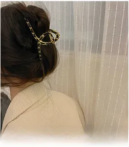 Detail of elegant gold metal chain woven with black ribbon hair claw clip for updos