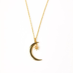 Detailed close-up of a gold-plated moon and opal star pendant on a fine link chain
