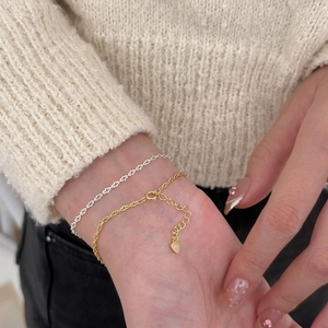 Detailed view of silver and gold S925 sterling silver heart bracelets on a model