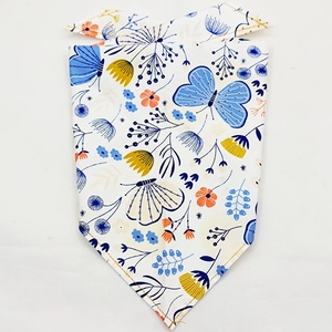 Flat lay of a white pet bandana featuring patterns of blue butterflies and yellow flowers