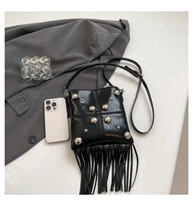 Detail of black leather crossbody bag with silver studs and long fringe tassels