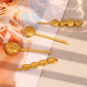 Detailed view of 18K gold plated seashell and starfish hair clips on a textured background