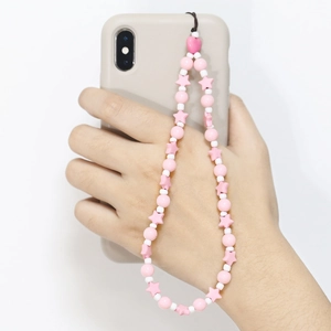 Pink and white acrylic beaded phone strap with heart and star charms held by hand