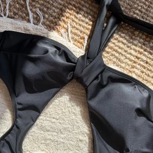 Detailed close-up of a black swimsuit top featuring a stylish front twist knot design