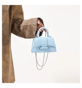 Detail showing light blue mini handbag with litchi texture and silver ball chain