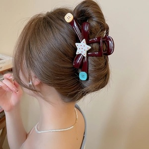 Detail of dark brown hair claw clip with star and button accents in a stylish hair bun