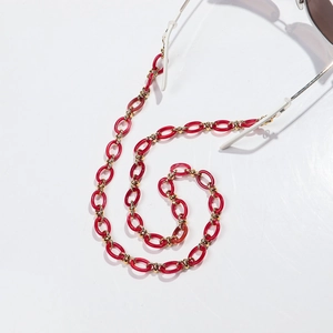 Detail of red acrylic resin links and gold metal clasp on a stylish eyewear chain