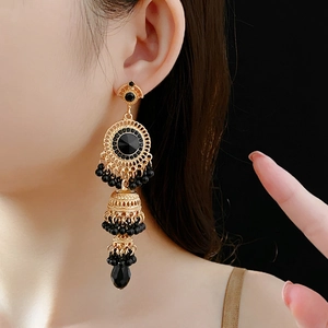 Macro detail of vintage gold earrings with black crystal teardrops worn by a model