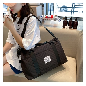 Detail of black quilted travel bag with reinforced handles and adjustable strap