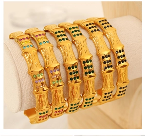 Detail view of golden bamboo style bangles with green and black rhinestones