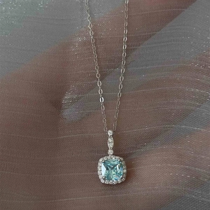 Macro shot of a silver necklace featuring a square blue halo pendant on grey tulle