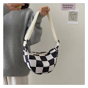 Detail of checkered crescent bag with adjustable strap shown in a lifestyle setting