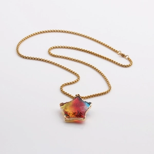 Macro detail of star pendant with multicolor faceted glass and golden box chain necklace