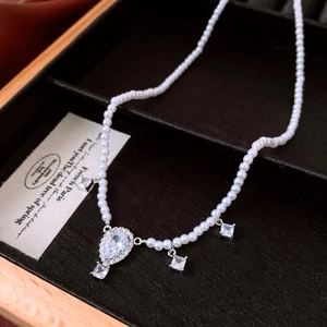 Detailed shot of teardrop zircon pendant and pearls in a premium jewelry gift box