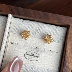 Macro detail of elegant gold floral cluster earrings with pearls and zircon in a jewelry box