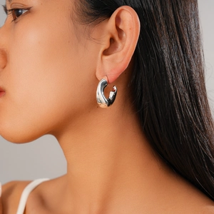 Primo piano di orecchini a cerchio ritorti a forma di C in argento su modella