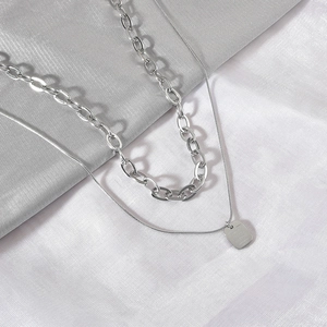 Double-layered silver necklace with bold chain and square pendant on a snake chain