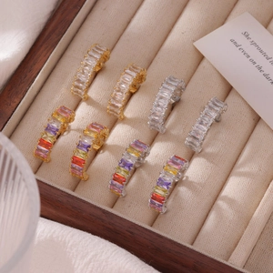 Boucles d'oreilles en zircon coloré doré et argenté sur un plateau à bijoux en bois