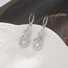 Macro detail of infinity silver drop earrings with pavé zircons and round crystal