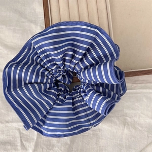 Blue and white striped scrunchie on a rustic tray for elegant low bun hairstyles