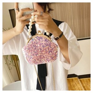 Close-up of pink sequin shell bag with large pearl handle and golden chain strap
