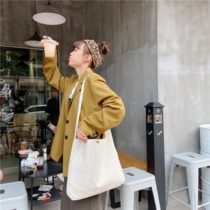Detailed view of white canvas shoulder bag with yellow daisy floral print in cafe setting