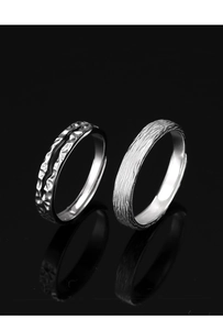 Detailed view of two vintage silver rings with hammered and brushed textures on black surface