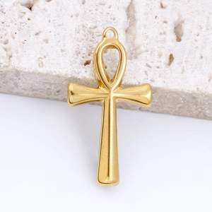 Macro shot of gold Ankh cross pendant on stone showing polished metal surface and details