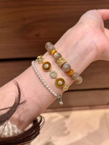 Détail de bracelets superposés en plaqué or avec perles d'acétate, nacre et zircons