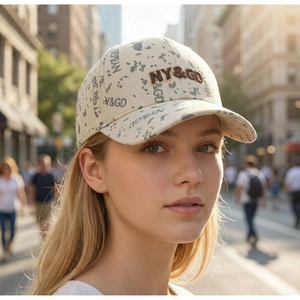 Gros plan d'une casquette beige avec broderie NY&GD et motif imprimé sur un mannequin.