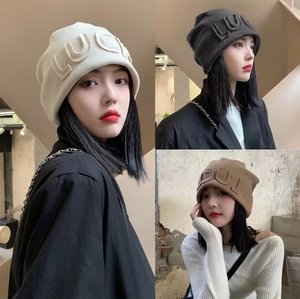 Detailed view of plush faux fur knitted winter hats in cream, black and khaki colors