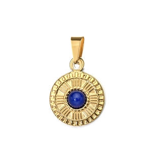 Close-up of golden vintage pendant with inlaid blue stone and geometric engravings