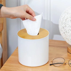 Detail showing a white cylindrical tissue box with a wooden lid on a desk setting