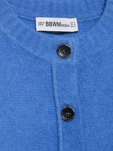 Detailed close-up of blue knit cardigan collar with black buttons and brand label