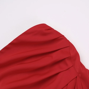 Detailed close-up of red satin fabric featuring intricate ruched texture and craftsmanship