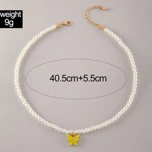 Detail of pearl necklace featuring a yellow butterfly pendant and adjustable clasp