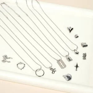 Collezione di collane Y2K in acciaio argento con pendenti a cuore e fiocco su un vassoio