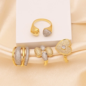 Copper heart and oval zircon rings set in gold and silver on silk background